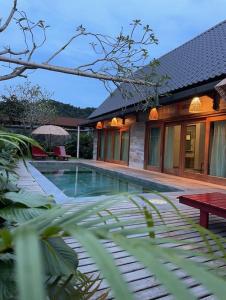 a swimming pool in front of a house at The Temak Villa in Pantai Cenang