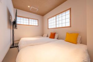 zwei Betten in einem Zimmer mit zwei Fenstern in der Unterkunft O's Apartment Hotel In Kyobashi 3FA in Osaka