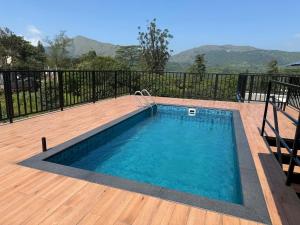 una piscina en una terraza con una terraza de madera en Monsoon Mist Kerala, en Pīrmed