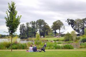 a group of people sitting on the grass in a park with a dog at ZEcamping 3 étoiles dog friendly bien-être piscine au bord dun lac in Loudéac