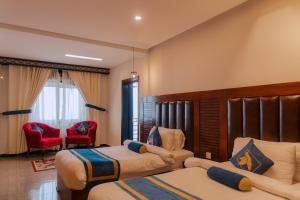 une chambre d'hôtel avec deux lits et une chaise rouge dans l'établissement Humming Bird Resort and Executive Suites, à Murree