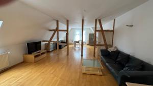 un salon avec un canapé noir et une télévision dans l'établissement Citywohnung in ruhiger Innenstadtnähe von Coburg, à Cobourg