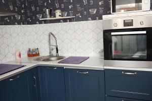 a kitchen with blue cabinets and a microwave at Maison en bord de mer in Réville +4 photos