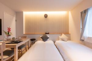 2 letti in una camera con scrivania e tavolo di O's Apartment Hotel In Kyobashi 3FB ad Osaka