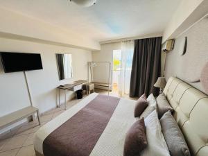 a hotel room with a bed and a television at Faedra Beach in Agios Nikolaos