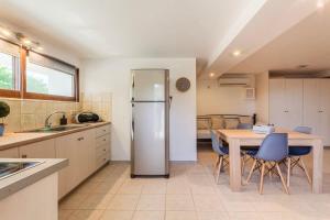 Una cocina con refrigerador y una mesa con sillas. en Mani's Aura Seaside-Enchanting Stone Gem, en Kotrónion