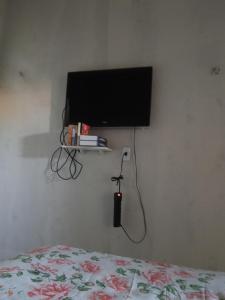 a bedroom with a bed and a television on a wall at Quarto e banheiro in Camocim