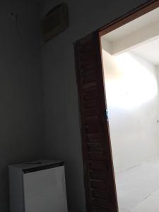 an open wooden door in a room with a refrigerator at Quarto e banheiro in Camocim