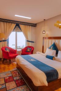 - une chambre avec un grand lit et deux chaises rouges dans l'établissement Humming Bird Resort and Executive Suites, à Murree