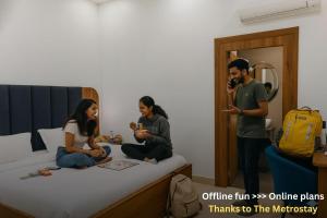 a man taking a picture of three people sitting on a bed at Metro POD Hotel at New Delhi Metro & Railway Station in New Delhi