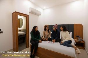 four women sitting on top of a bed at Metro POD Hotel at New Delhi Metro & Railway Station in New Delhi