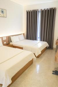 een hotelkamer met twee bedden en een raam bij Visip Hotel in Vinh +9 foto's