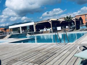a swimming pool with a wooden deck next to a building at La Villa Sylody in Lecci