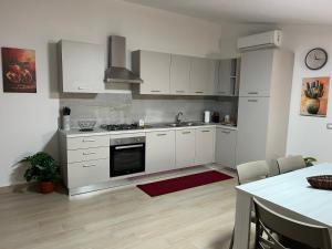 une cuisine avec des armoires blanches et un four à plaques de cuisson dans l'établissement Kalon Eidos, il magico posto della Calabria Jonica, à Condofuri Marina