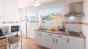 a kitchen with white cabinets and a sink and a window at Los Cortinales Setenil de las Bodegas by Ruralidays in Setenil