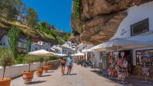 a group of people walking down a street next to a mountain at Los Cortinales Setenil de las Bodegas by Ruralidays in Setenil