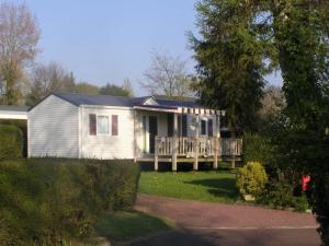 a small white house with a porch on a yard at ZEcamping 4 étoiles familial avec étang de pêche et piscine chauffée in La Haye-du-Puits