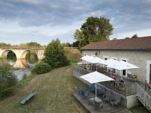 un bâtiment avec des tables et des parasols à côté d'une rivière dans l'établissement Camping 3 étoiles - Piscine - ccbb0if, à Montpon-Ménestérol