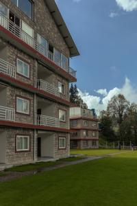 un immeuble d'appartements avec une pelouse devant dans l'établissement Humming Bird Resort and Executive Suites, à Murree