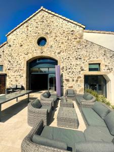 ein Gebäude mit einer Terrasse mit Sofas und Tischen in der Unterkunft "La Petite Félixière" à 25 min du Puy du Foù, 10 min de Cholet, et 35 min de Nantes in Saint-André-de-la-Marche