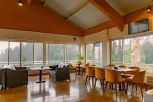 un restaurant avec des tables et des chaises et de grandes fenêtres dans l'établissement Humming Bird Resort and Executive Suites, à Murree