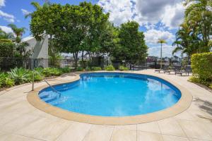 ゴールドコーストにあるPalms on Gold - Sun, Swims & Riverside Viewsの椅子と木々のある庭のスイミングプール