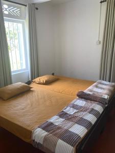a bedroom with two beds and a window at Cityscape Bungalow in Bandarawela