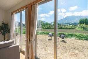 a room with a large glass window with a couch and chairs at 阿蘇ビューテラス in Aso +42 photos