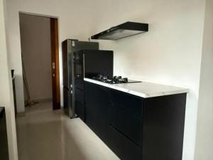 a kitchen with black cabinets and a refrigerator at Villa Rob in Kerobokan