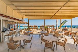 a restaurant with tables and chairs on the beach at Lotus Serenity Suites in Amoudara Herakliou