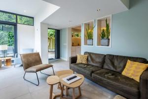 ein Wohnzimmer mit Ledersofa und Sesseln in der Unterkunft Hello Zeeland - Vroonweg 34 in Oostkapelle