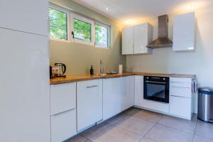 eine weiße Küche mit weißen Schränken und einem Herd in der Unterkunft Hello Zeeland - Vroonweg 34 in Oostkapelle