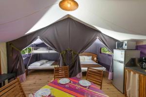 a tent with a table and two beds in it at Chalet 3 étoiles - Piscine - ccbbhfa in Clohars-Carnoët