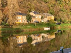 a house next to a river with reflections in the water at Maison authentique en bord de Meuse in Joigny-sur-Meuse