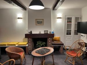 a living room with a fireplace and a table and chairs at Maison authentique en bord de Meuse in Joigny-sur-Meuse