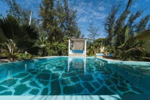 a swimming pool in a backyard with trees and bushes at GK Palm Resort Watamu in Watamu