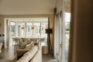 un soggiorno con un divano e un tavolo con sedie di Watervilla buitenzijde | 6 personen a Heeg Altre 21 foto