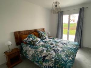 a bedroom with a bed with a flowered comforter and a window at Le gîte des Acacias in Montech