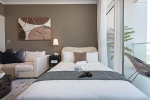 ein Schlafzimmer mit einem großen weißen Bett und einer Couch in der Unterkunft StayShort - Spacious Carson C Studio in Damac Hills in Dubai Marina