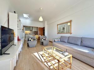 un soggiorno con un divano e una TV di Quarteira Central 3 by Homing a Cavacos