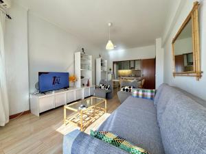 un soggiorno con un divano blu e una TV di Quarteira Central 3 by Homing a Cavacos