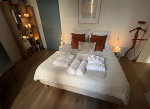 un lit blanc avec des serviettes et des oreillers dessus dans l'établissement Les Capucines, comme chez soi, loin de chez soi, à Aubenas