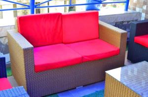 une chaise en osier avec un siège rouge sur une terrasse dans l'établissement Chinbell Luxury Hotel & Suites, à Wamba