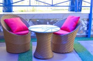 trois chaises en osier avec des coussins roses et une table dans l'établissement Chinbell Luxury Hotel & Suites, à Wamba