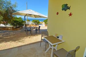 a patio with a table and chairs and an umbrella at B&B Lu Cantoru in Marina di Pescoluse
