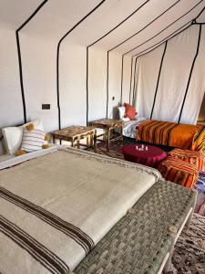 a room with two beds and tables in a tent at Bivouac Luna in Mhamid