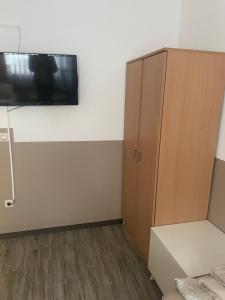 a room with a tv on the wall and a cabinet at LIVI Hostel und Pension in Dortmund