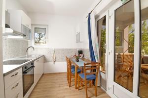 a kitchen with white cabinets and a table and chairs at apartmani Novotny crveni in Banjol