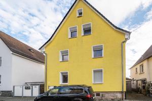 een geel huis met een auto ervoor geparkeerd bij Az-Living Heppenheim in Heppenheim an der Bergstrasse