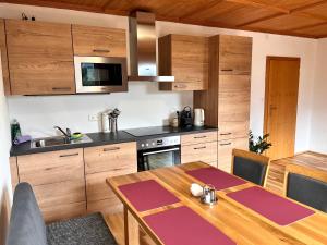 eine Küche mit Holzschränken und einem Holztisch in der Unterkunft Appartements-Restaurant Schwaiger direkt beim Lift und wunderschönen Bergblick in Tauplitz